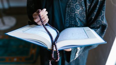 crop photo of woman holding a prayer beads and holy book